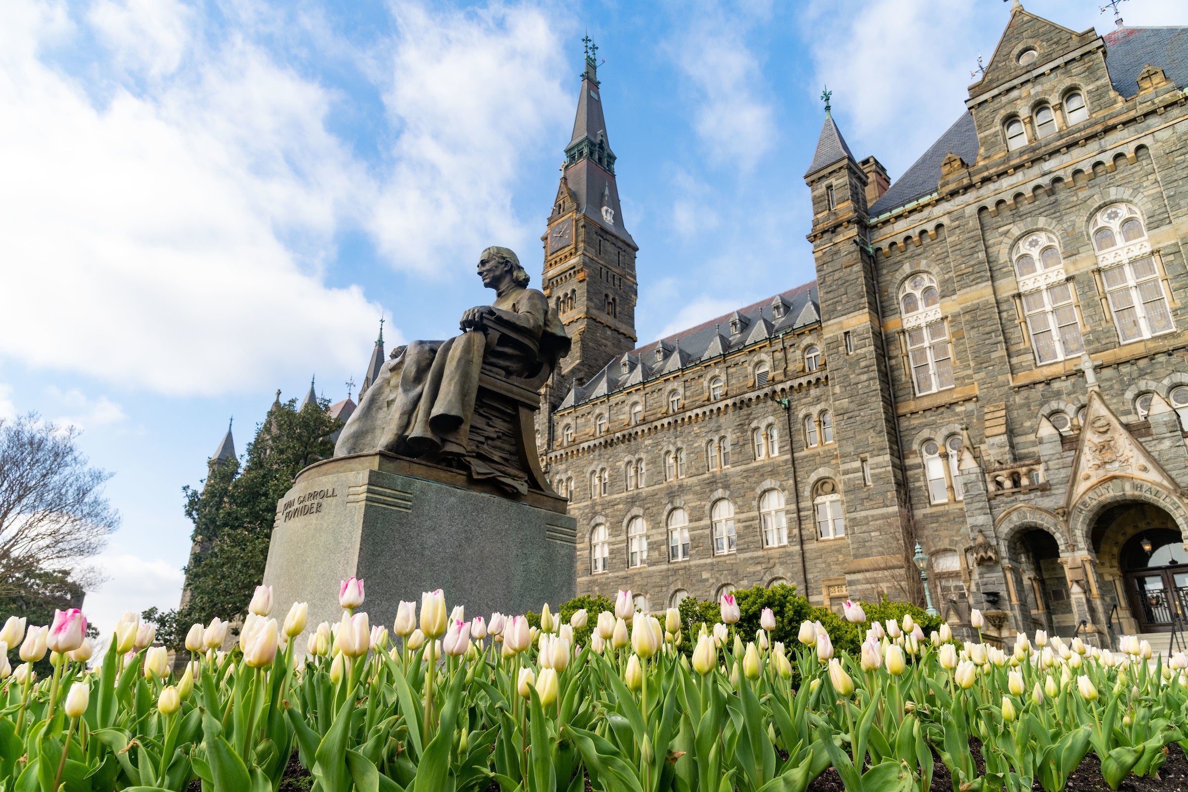 John Carroll statue surrounded by flowers in front of Healy Hall.